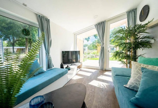 Sala luminosa en Panorama Cottage 4 con grandes ventanales, decoración moderna y vistas verdes en los Países Bajos.