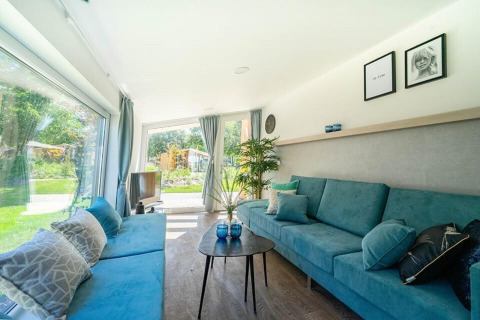 Sala luminosa de Panorama Cottage 4 en De Utrechtse Heuvelrug, Países Bajos, con vista al jardín.