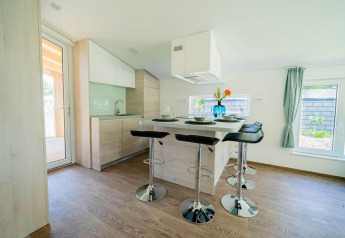 Moderne, lichte lodgekeuken met bar en krukken in Panorama Cottage 4, De Utrechtse Heuvelrug, Nederland.