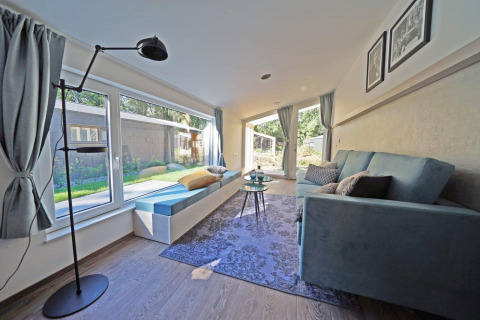 Salon lumineux et moderne du Panorama Cottage 4 à De Utrechtse Heuvelrug, Pays-Bas, avec grandes fenêtres et vue sur le jardin.