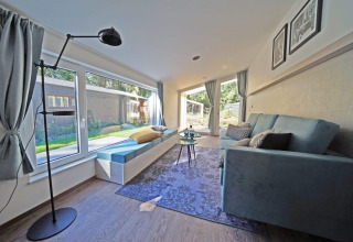 Salón luminoso y moderno en Panorama Cottage 4 de De Utrechtse Heuvelrug, Países Bajos, con grandes ventanas y vista al jardín.