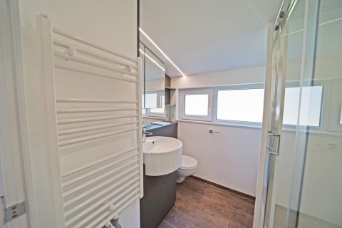 Salle de bain moderne avec sol effet bois, lavabo, grand miroir, douche et fenêtres à Panorama Cottage 4, Pays-Bas.