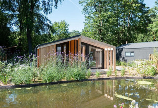 Moderne lodge ved navn Panorama Cottage 4 ved De Utrechtse Heuvelrug i Holland, omgivet af natur og dam.