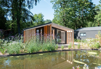 Moderne lodge ved navn Panorama Cottage 4 ved De Utrechtse Heuvelrug i Holland, omgivet af natur og dam.
