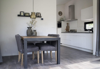 Alojamiento glamping moderno con mesa de comedor, sillas cómodas y cocina blanca de diseño elegante.