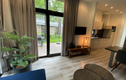 Modern living room in Pavilion 6 at De Utrechtse Heuvelrug, Netherlands, featuring terrace and garden view.