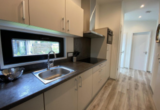 Cocina moderna en el Pavilion 6 de De Utrechtse Heuvelrug, Países Bajos, con suelo de madera y ventana.