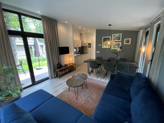 Modern living room and kitchen in Pavilion 6, De Utrechtse Heuvelrug, Netherlands, with large windows and stylish decor.