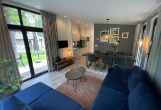 Modern living room and kitchen in Pavilion 6, De Utrechtse Heuvelrug, Netherlands, with large windows and stylish decor.