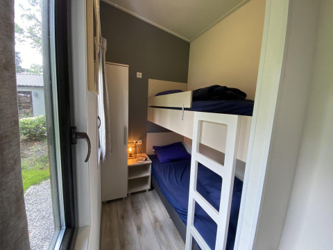 Habitación estrecha con literas, ropa de cama azul, armario y mesita en Pavilion 6, De Utrechtse Heuvelrug.
