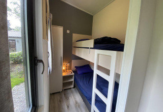 Habitación estrecha con literas, ropa de cama azul, armario y mesita en Pavilion 6, De Utrechtse Heuvelrug.