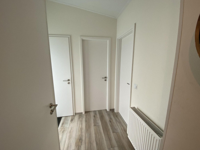 Hallway with three white doors and wooden flooring in Pavilion 6 at De Utrechtse Heuvelrug, Netherlands.