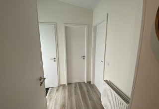 Hallway with three white doors and wooden flooring in Pavilion 6 at De Utrechtse Heuvelrug, Netherlands.