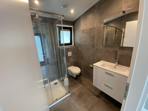 Modern bathroom in Pavilion 6 at De Utrechtse Heuvelrug, Netherlands, featuring glass shower and wall toilet.
