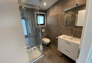 Modern bathroom in Pavilion 6 at De Utrechtse Heuvelrug, Netherlands, featuring glass shower and wall toilet.