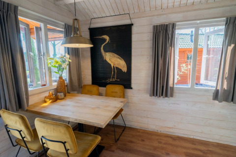 Gezellige eethoek in Stuga 4 bij De Utrechtse Heuvelrug, Nederland, met houten tafel en kunst aan de muur.
