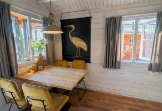 Gezellige eethoek in Stuga 4 bij De Utrechtse Heuvelrug, Nederland, met houten tafel en kunst aan de muur.