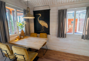 Acogedor comedor en Stuga 4 de De Utrechtse Heuvelrug, Países Bajos, con mesa de madera y decoración natural.