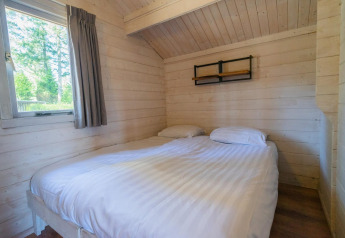 Camera minimalista in legno con letto matrimoniale e finestra, Stuga 4, De Utrechtse Heuvelrug, Paesi Bassi.