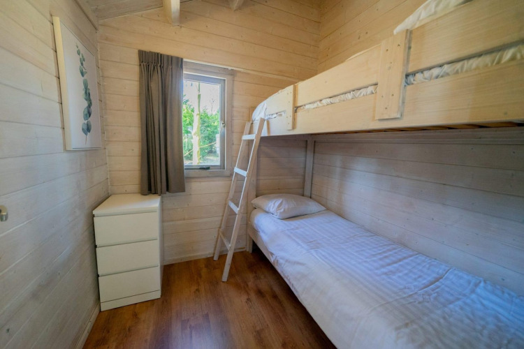 Ein helles Zimmer in Stuga 4 bei De Utrechtse Heuvelrug in den Niederlanden mit Etagenbett und Kommode.