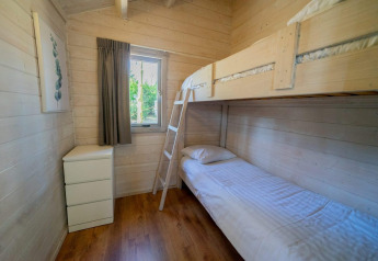 Habitación luminosa en Stuga 4 de De Utrechtse Heuvelrug, Países Bajos, con litera y cajonera blanca.