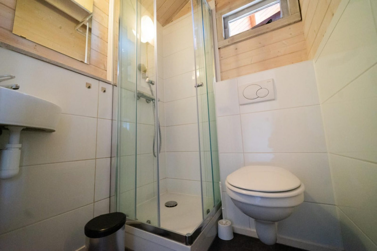 Kleines Badezimmer mit Duschkabine, Wandtoilette und Waschbecken in Stuga 4, De Utrechtse Heuvelrug, Niederlande.