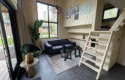 Acogedora sala de Tiny House 4 en De Utrechtse Heuvelrug, Países Bajos, con muebles modernos y altillo.