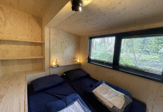 Camera da letto di tiny house moderna con due letti, grandi finestre e pareti in legno chiaro a De Utrechtse Heuvelrug, Paesi Bassi.