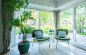 Bright lounge in Velthorst 4 lodge at De Utrechtse Heuvelrug, Netherlands, with green chairs and garden view.