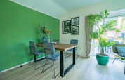 Dining area in lodge Velthorst 4 at De Utrechtse Heuvelrug, Netherlands, with green accent wall and plants.