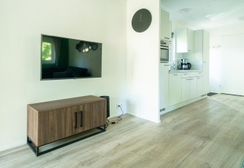 Moderne lodge woonkamer met flatscreen-tv, houten kast en keuken in Velthorst 4, De Utrechtse Heuvelrug.