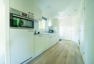 Moderne witte keuken met oven en koffiezet in Velthorst 4, De Utrechtse Heuvelrug, Nederland.