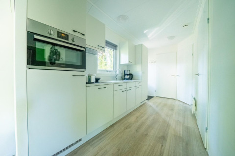 Modern white kitchen with built-in oven and coffee maker at Velthorst 4, De Utrechtse Heuvelrug, Netherlands.
