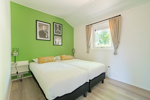 Lichte slaapkamer in Velthorst 4, De Utrechtse Heuvelrug, Nederland, met groene muur en twee aparte bedden.