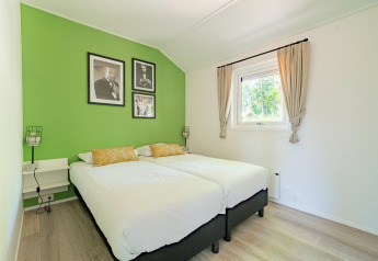 Lichte slaapkamer in Velthorst 4, De Utrechtse Heuvelrug, Nederland, met groene muur en twee aparte bedden.