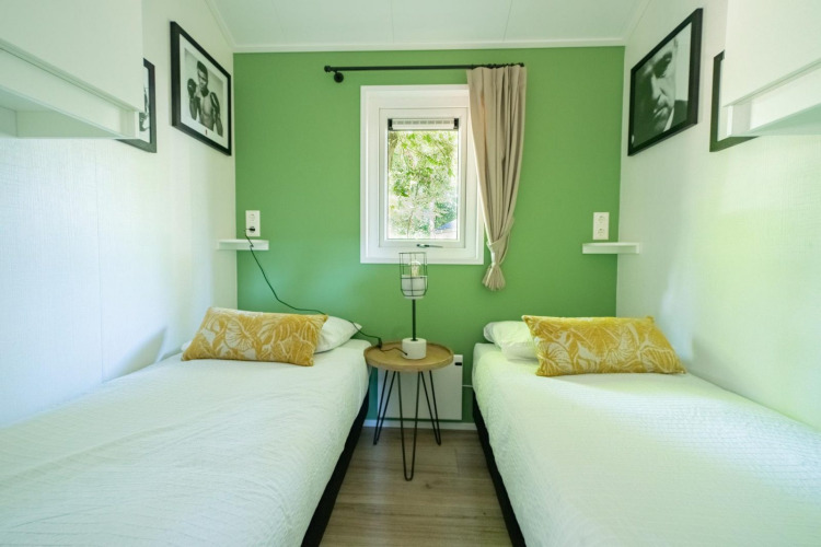 Bedroom at Velthorst 4 lodge in De Utrechtse Heuvelrug, Netherlands with two single beds and green accent wall.