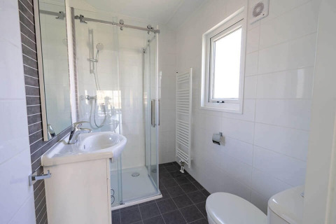 Moderne badkamer met douche, lavabo, toilet en raam in Velthorst 4, De Utrechtse Heuvelrug, Nederland.