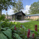 En moderne lodge ved navn Velthorst 6 med store vinduer, terrasse og frodig have omgivet af natur.