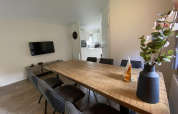 Modern dining area with wooden table and six chairs in Velthorst 6 lodge at De Utrechtse Heuvelrug, Netherlands.