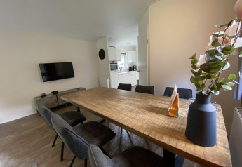 Salle à manger moderne avec table en bois et six chaises dans le lodge Velthorst 6 à De Utrechtse Heuvelrug, Pays-Bas.