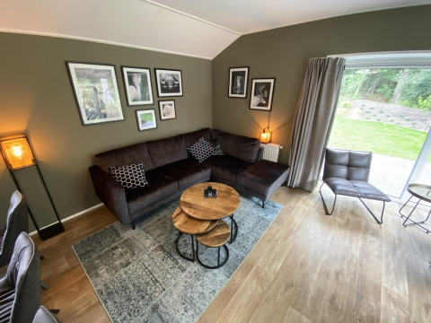 Moderne woonkamer in Velthorst 6 lodge bij De Utrechtse Heuvelrug, Nederland, met bank en wanddecoratie.