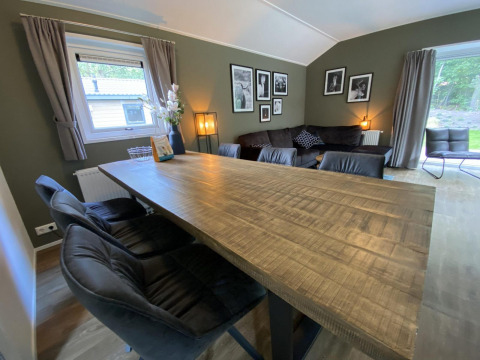 Woonkamer in Velthorst 6 lodge bij De Utrechtse Heuvelrug, Nederland, met houten tafel en banken.