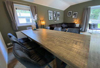 Woonkamer in Velthorst 6 lodge bij De Utrechtse Heuvelrug, Nederland, met houten tafel en banken.