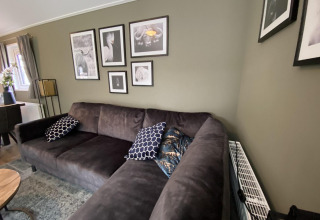 Sala moderna en la Velthorst 6, De Utrechtse Heuvelrug, Países Bajos, con sofá y cuadros en la pared.