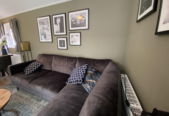 Sala moderna en la Velthorst 6, De Utrechtse Heuvelrug, Países Bajos, con sofá y cuadros en la pared.