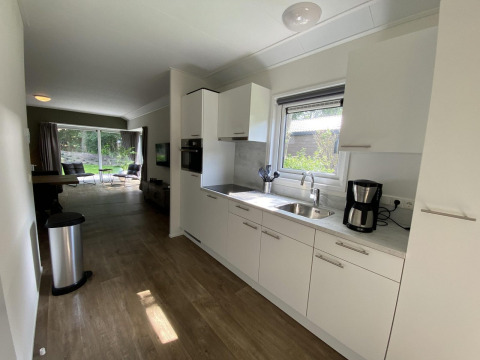 Moderne keuken en woonkamer in Velthorst 6 lodge op De Utrechtse Heuvelrug, Nederland, met uitzicht op tuin.
