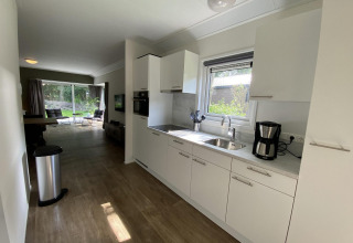 Moderne keuken en woonkamer in Velthorst 6 lodge op De Utrechtse Heuvelrug, Nederland, met uitzicht op tuin.