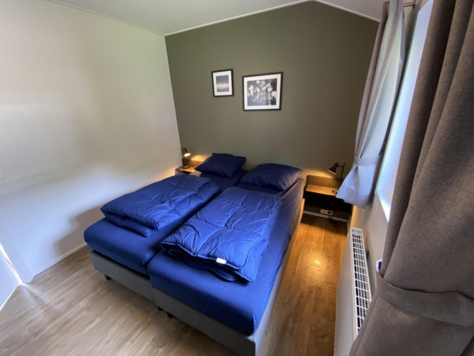 Gemütliches Schlafzimmer in Velthorst 6 mit zwei Einzelbetten, blauer Bettwäsche und Wandbildern.