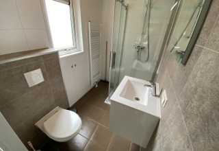 Baño moderno y compacto en Velthorst 6 lodge con ducha, lavabo e inodoro en De Utrechtse Heuvelrug, Países Bajos.