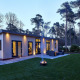 Cubus Lodge ved Bospark Markelo i Holland, moderne sommerhus omgivet af skov under aftenskumring.